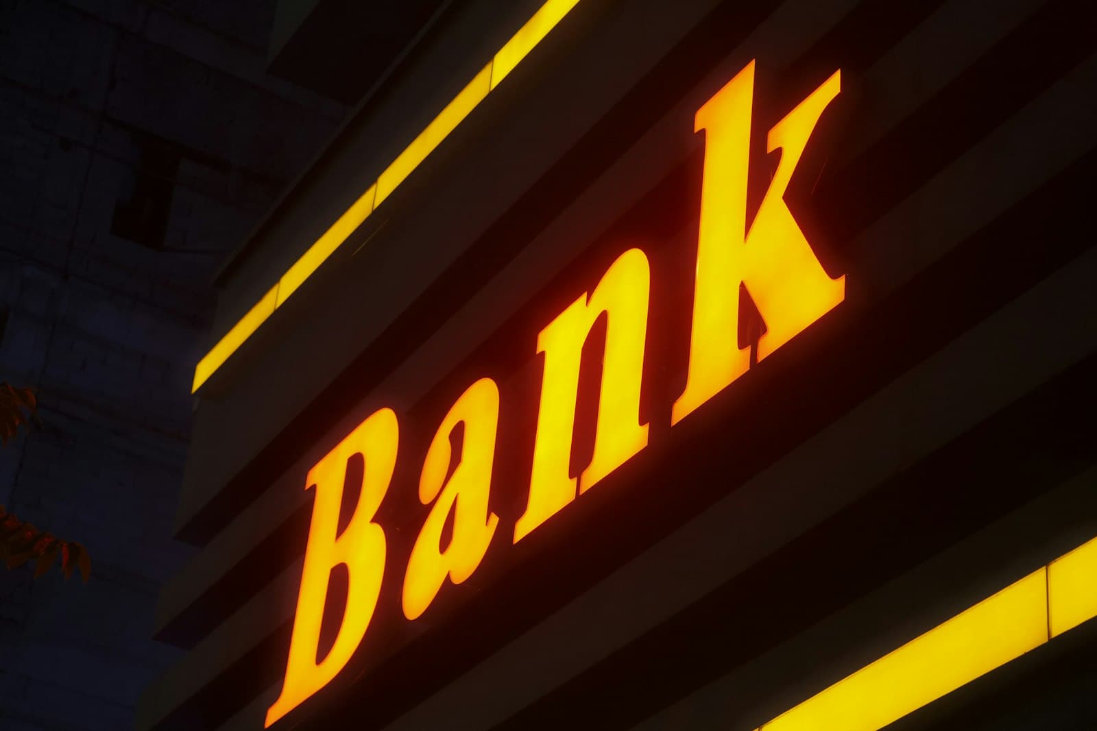 An illuminated 'Bank' signage glowing on the exterior of a building at night
