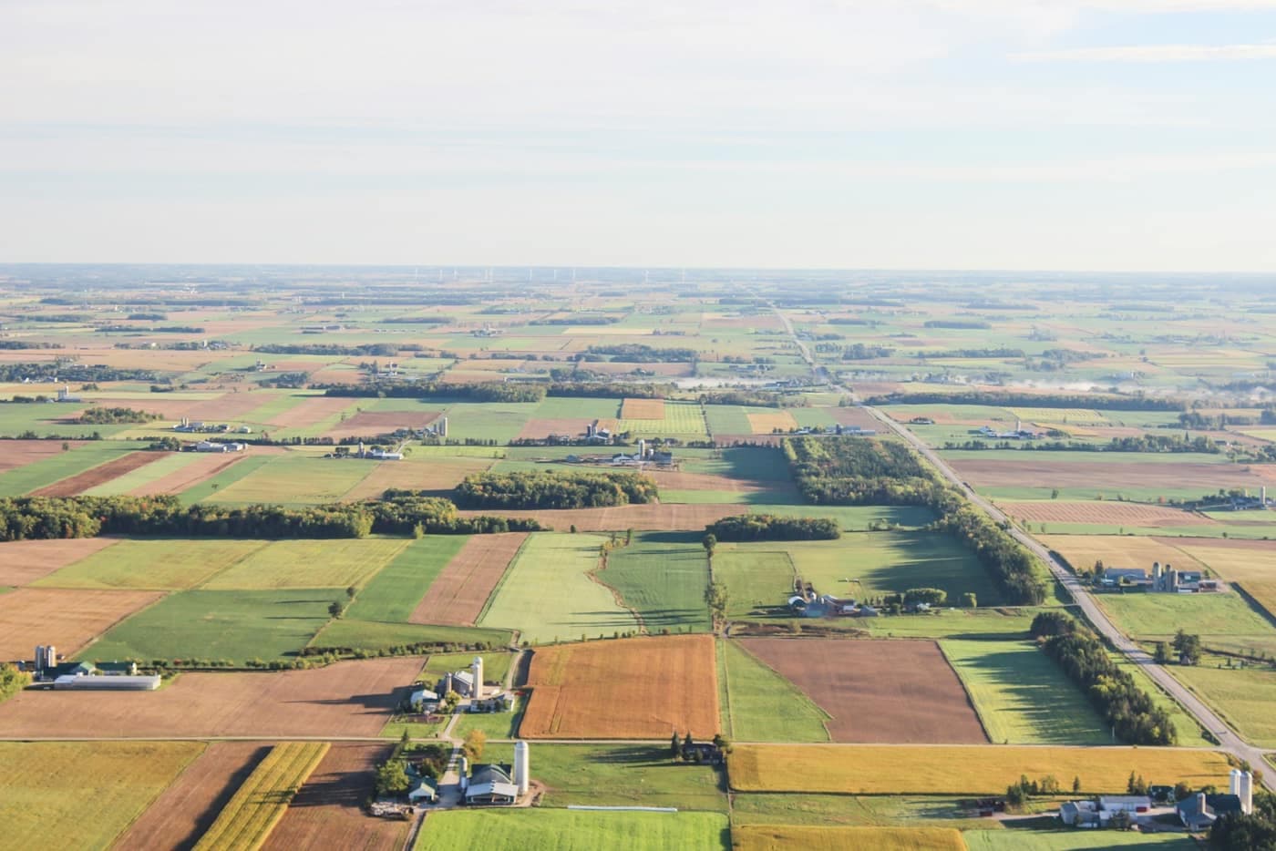 Aerial view of large farm fields divided into distinct rectangular zones of differing brown and green shades
