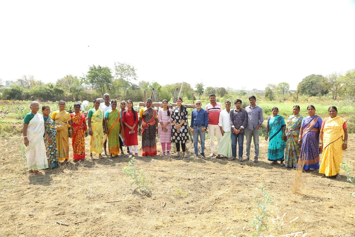 A group of Indian farmers standing together outdoors in an agricultural field for a village extension gathering