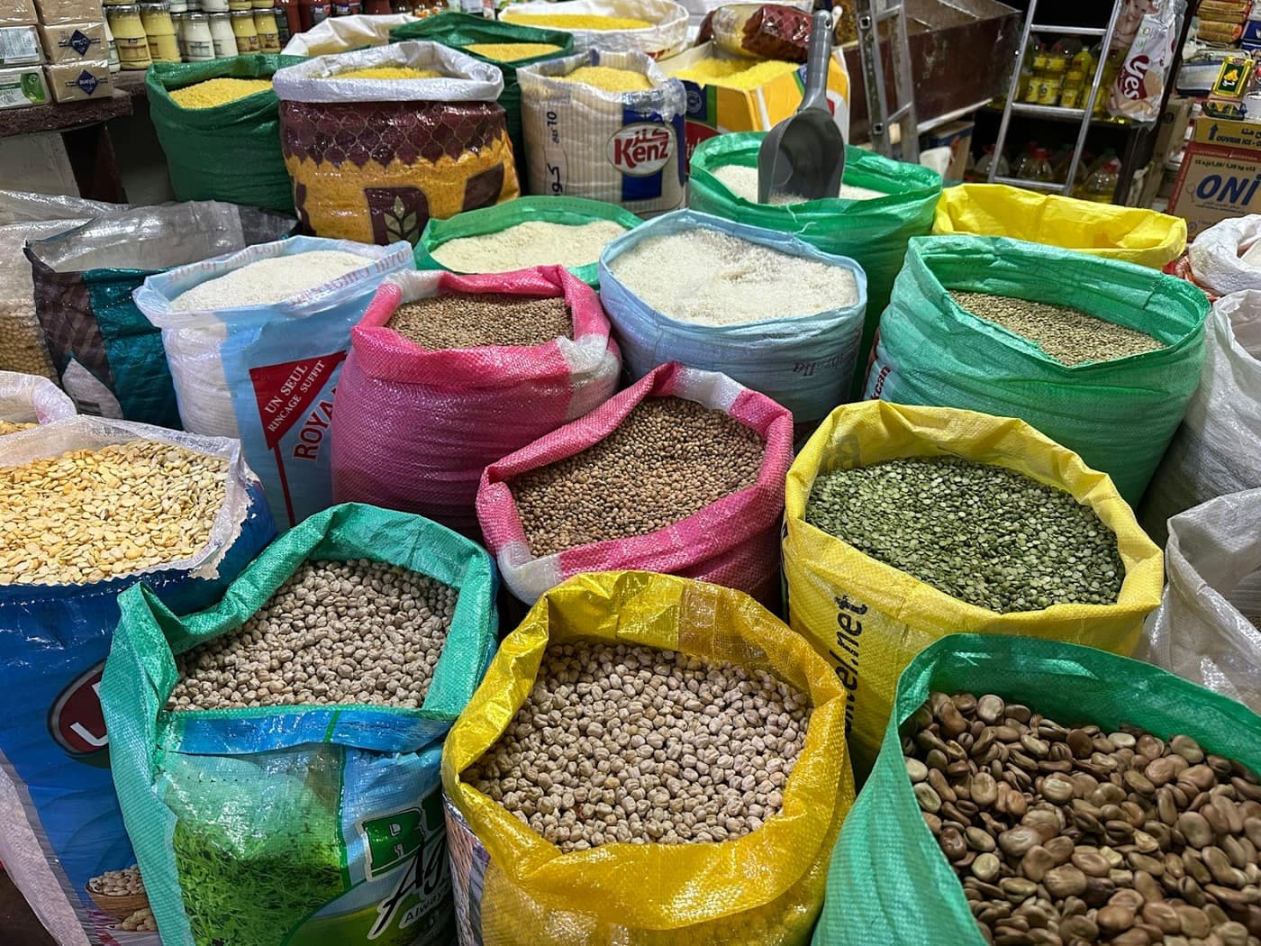 Open sacks of assorted grains, lentils and pulses lined up on the floor of a market stall