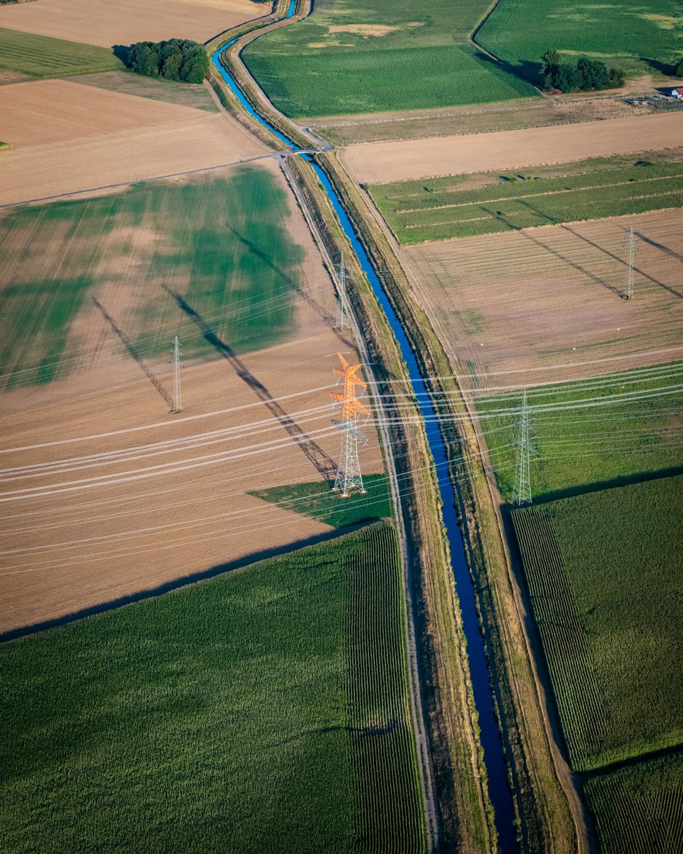 Aerial view of an irrigation canal running past cultivated fields and electrical transmission lines