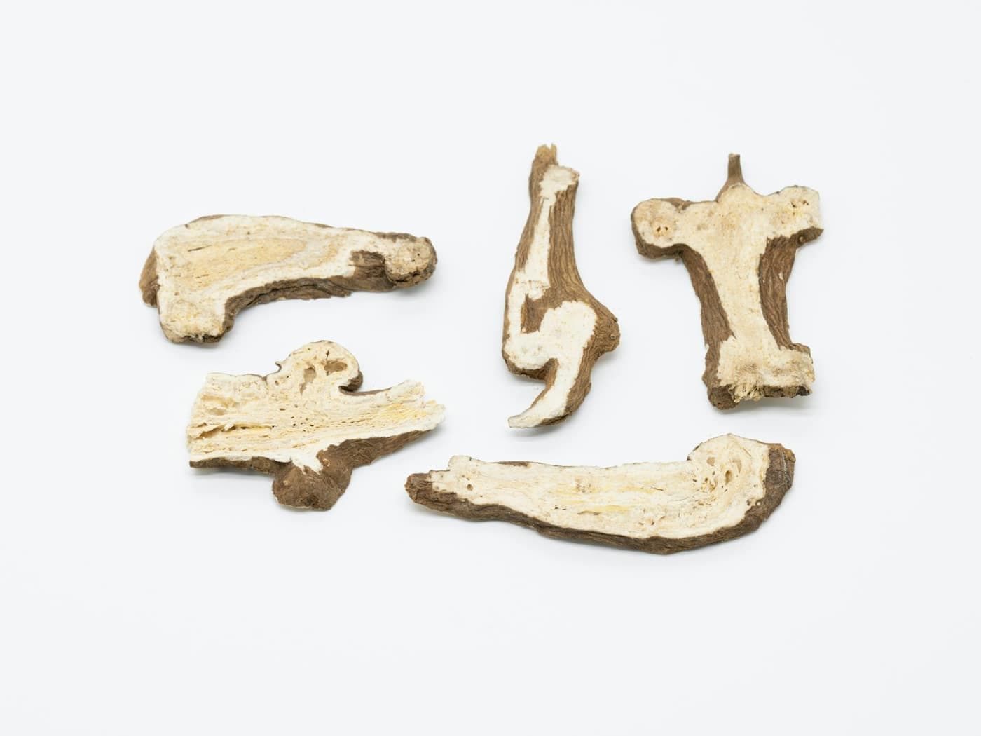 Pale, sliced pieces of a dried medicinal herb root laid out on a white surface — a generic stand-in, not a confirmed photo of Safed Musli itself