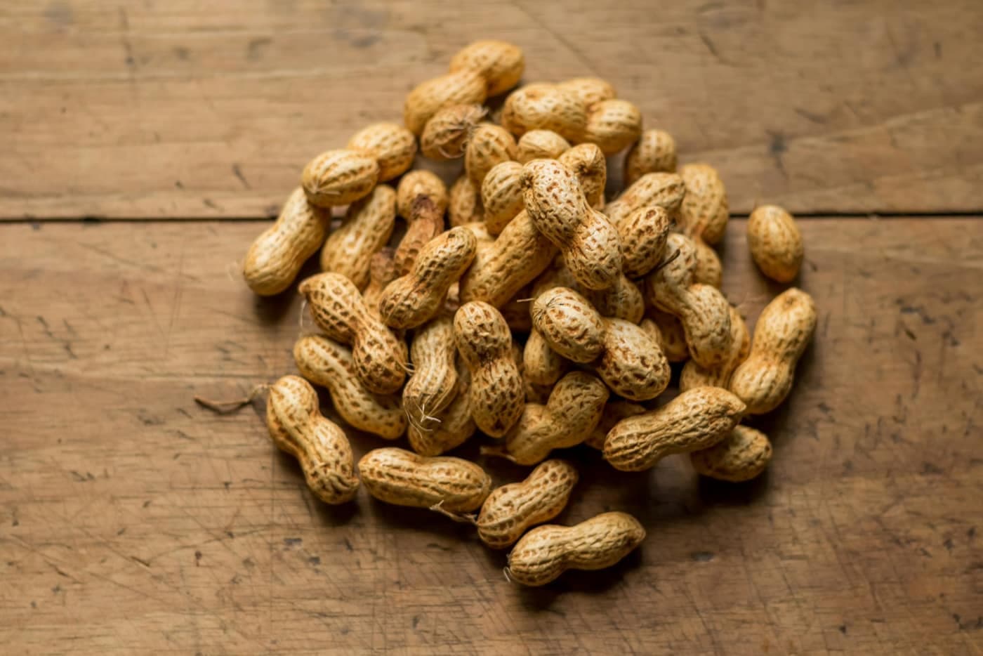 A pile of unshelled brown peanuts (groundnuts)