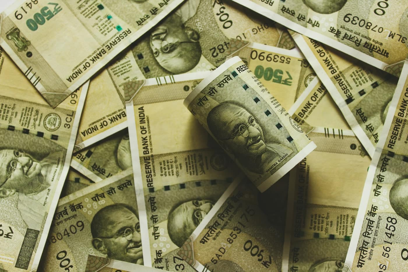 A pile of Indian five-hundred-rupee banknotes with one note rolled up in the centre