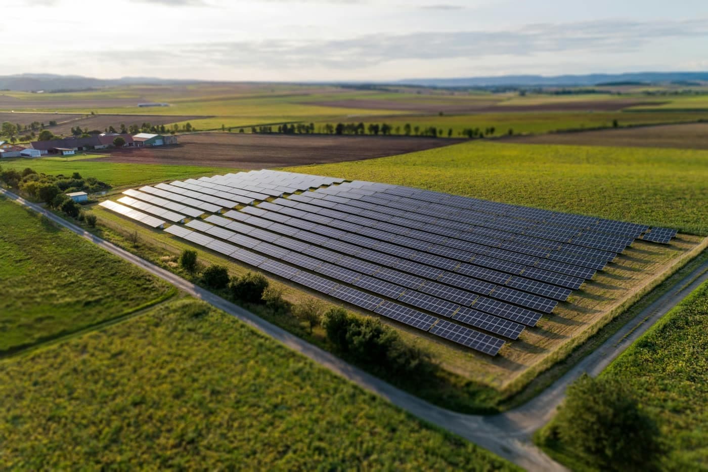 Aerial view of a rectangular solar panel array installed amid green farmland